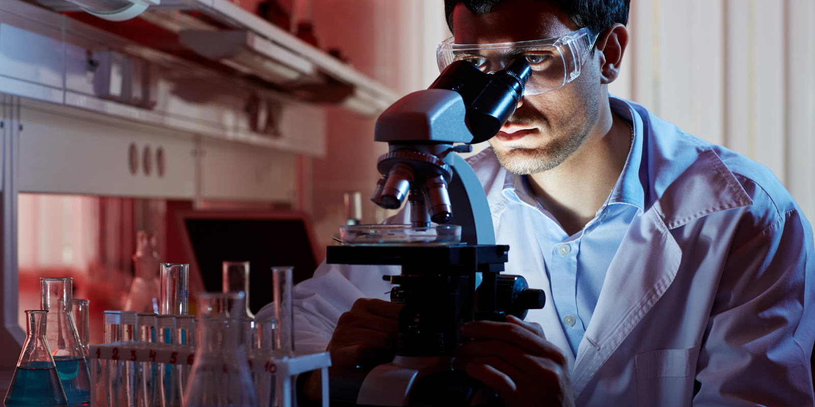 Man working in a lab looking through a microscope