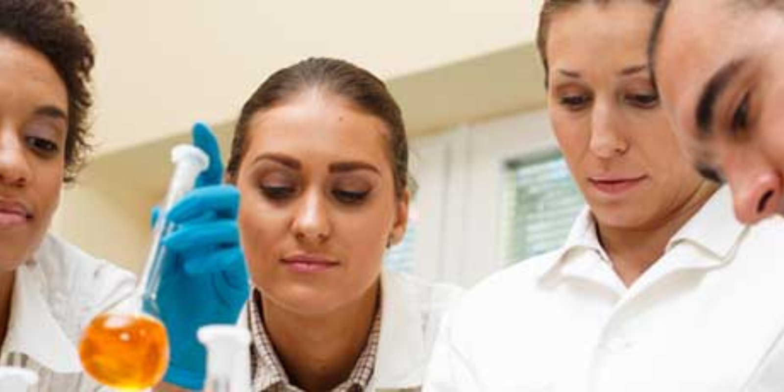 a group of people looking at a beaker